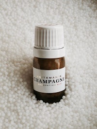 a bottle of champagne essential oil sitting on a bed of white powder