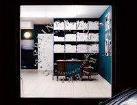 a dark room with a window showing a room full of books