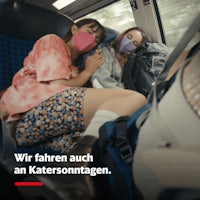 two women are sleeping on a train with a mask on their faces