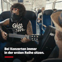 a man sitting on a train with a guitar