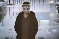 a man in a hoodie is standing in front of a large screen